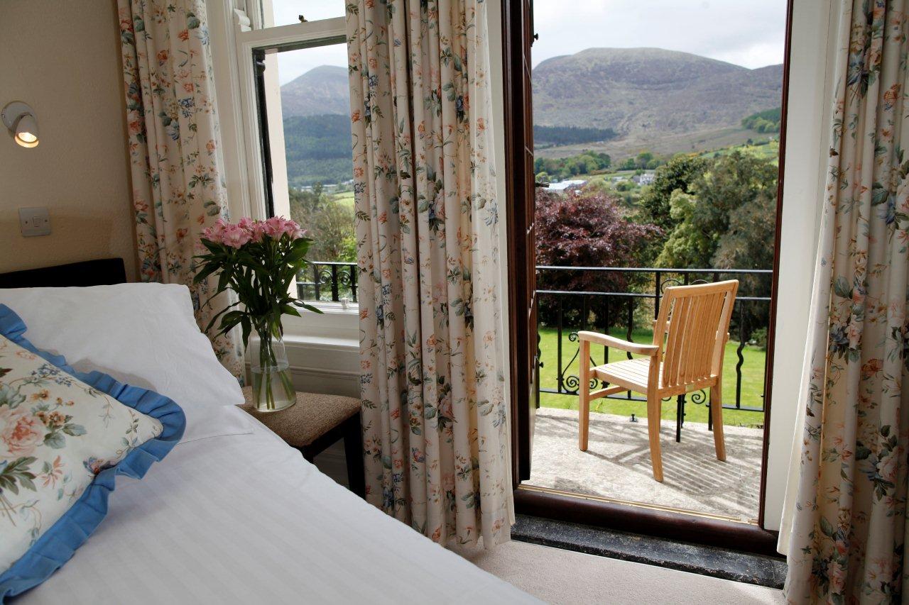 A bedroom's french doors open onto a balcony overlooking the Shimna Valley and the Mourne Mountains
