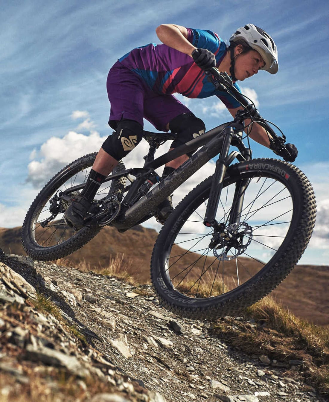 A mountain biker descends a rocky trail on a Trek full-suspension bike