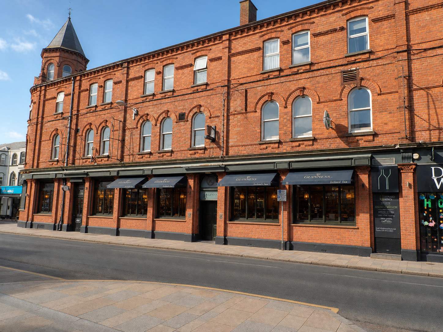 Faithful visualisation of The Donard's red-brick Main Street frontage and corner turret, with the ground-floor shutters open
