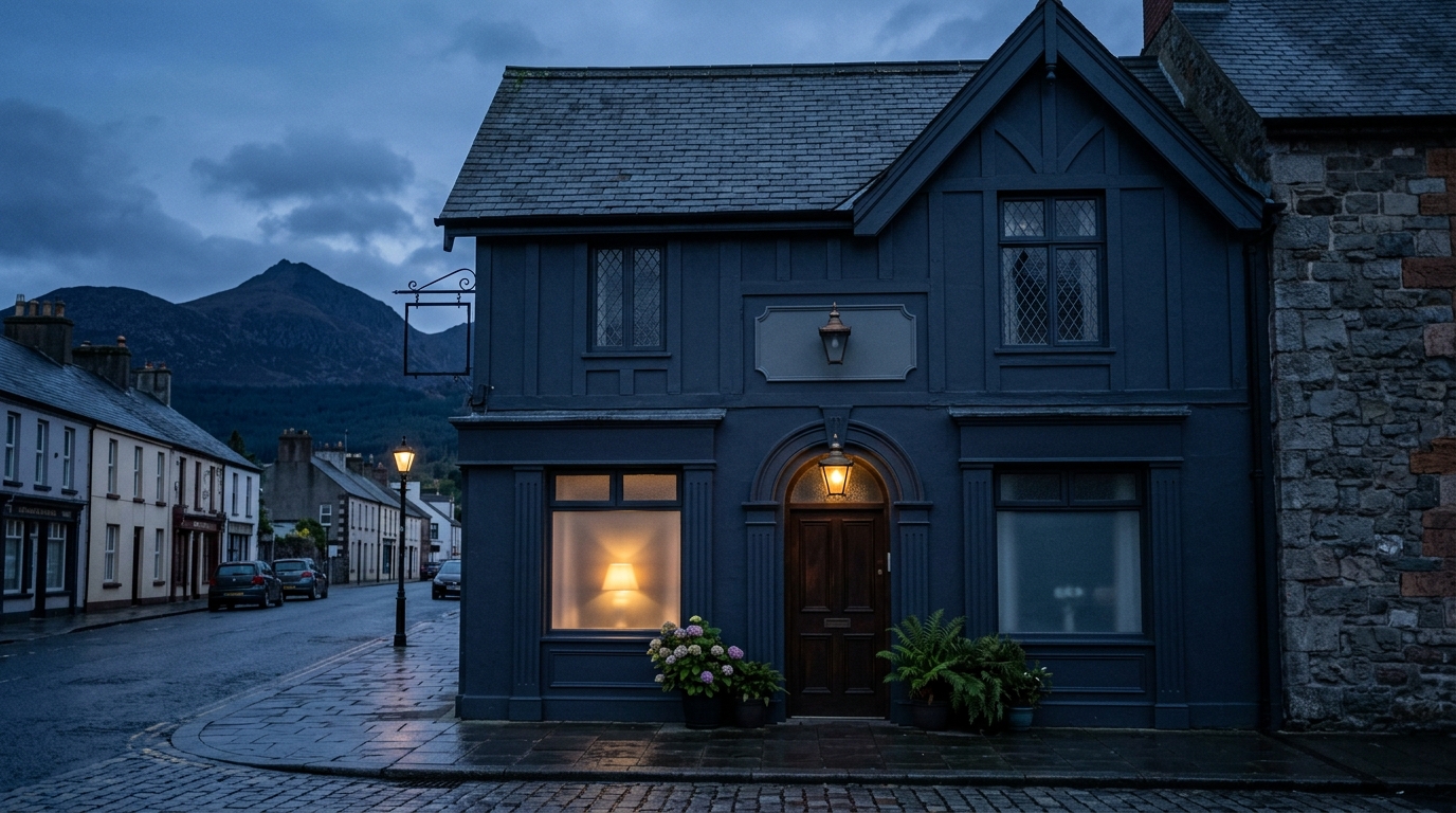 Dignified independent funeral home exterior on Main Street in Newcastle during quiet blue hour twilight with a warm glowing lamp behind frosted windows